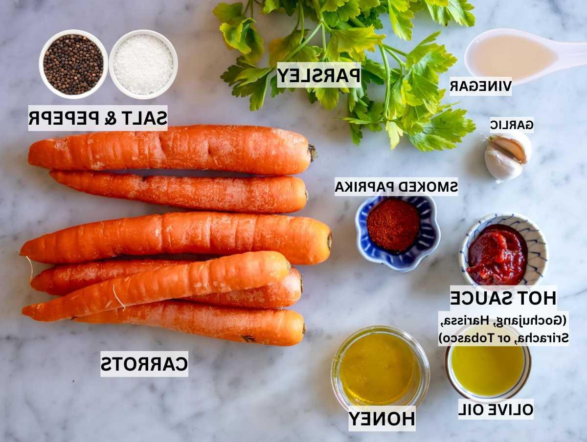 Zutaten für geröstete Karotten auf einem Marmortisch.