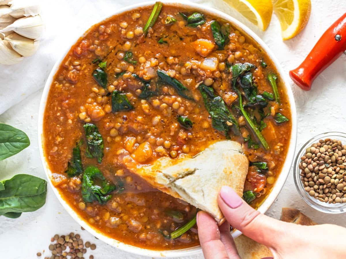 Einfache Linsen-Gemüsesuppe mit Hand, die Pitabrot hält