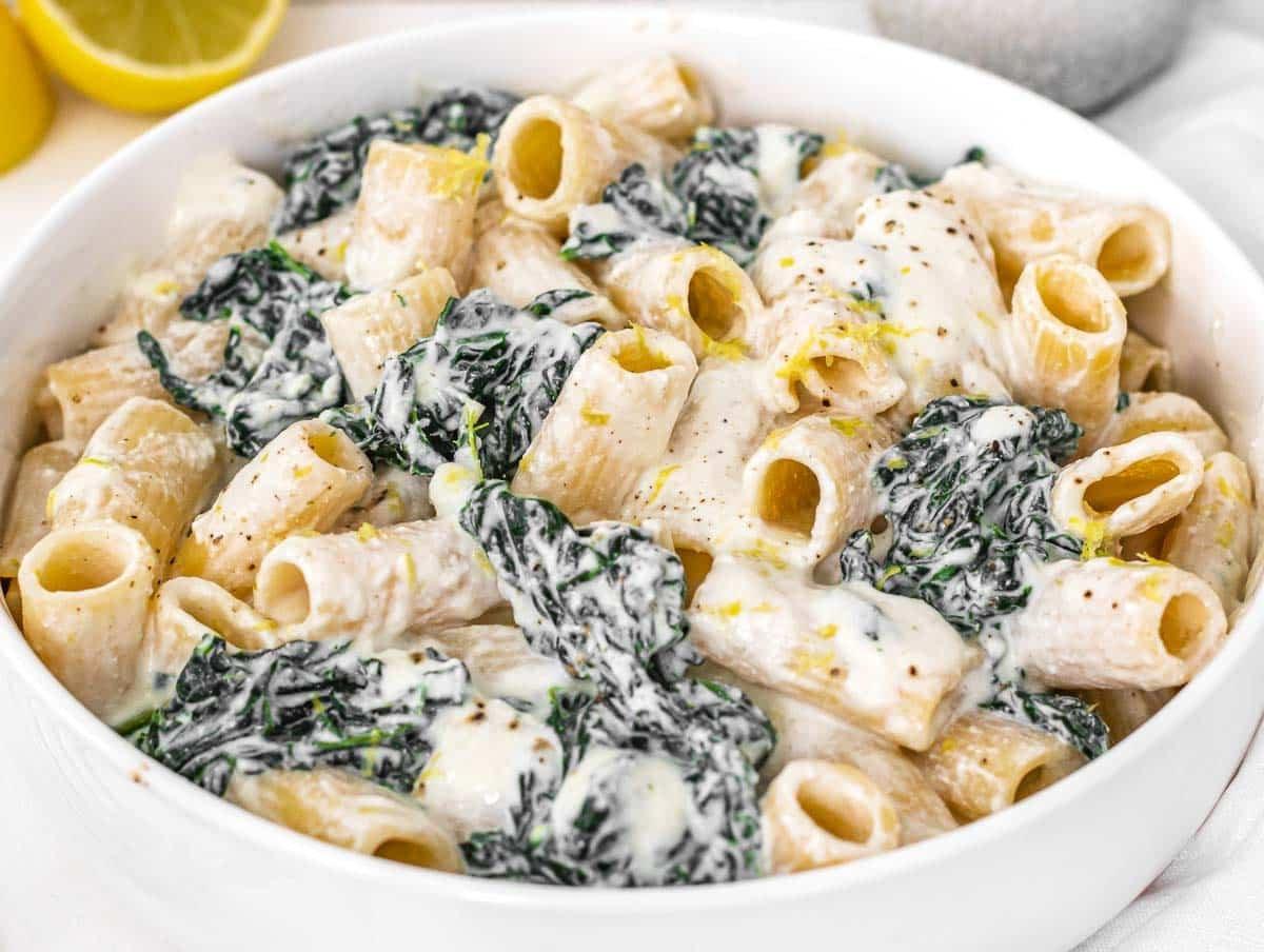 Cremige Grünkohl-Pasta in einer weißen Schüssel mit Zitrone