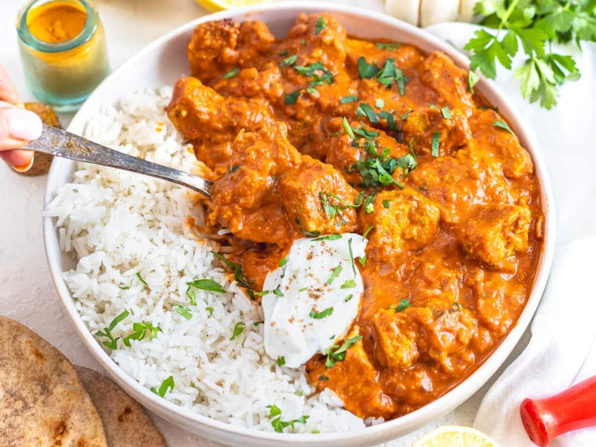 Tofu Tikka Masala mit einem Klecks Joghurt und einem silbernen Löffel