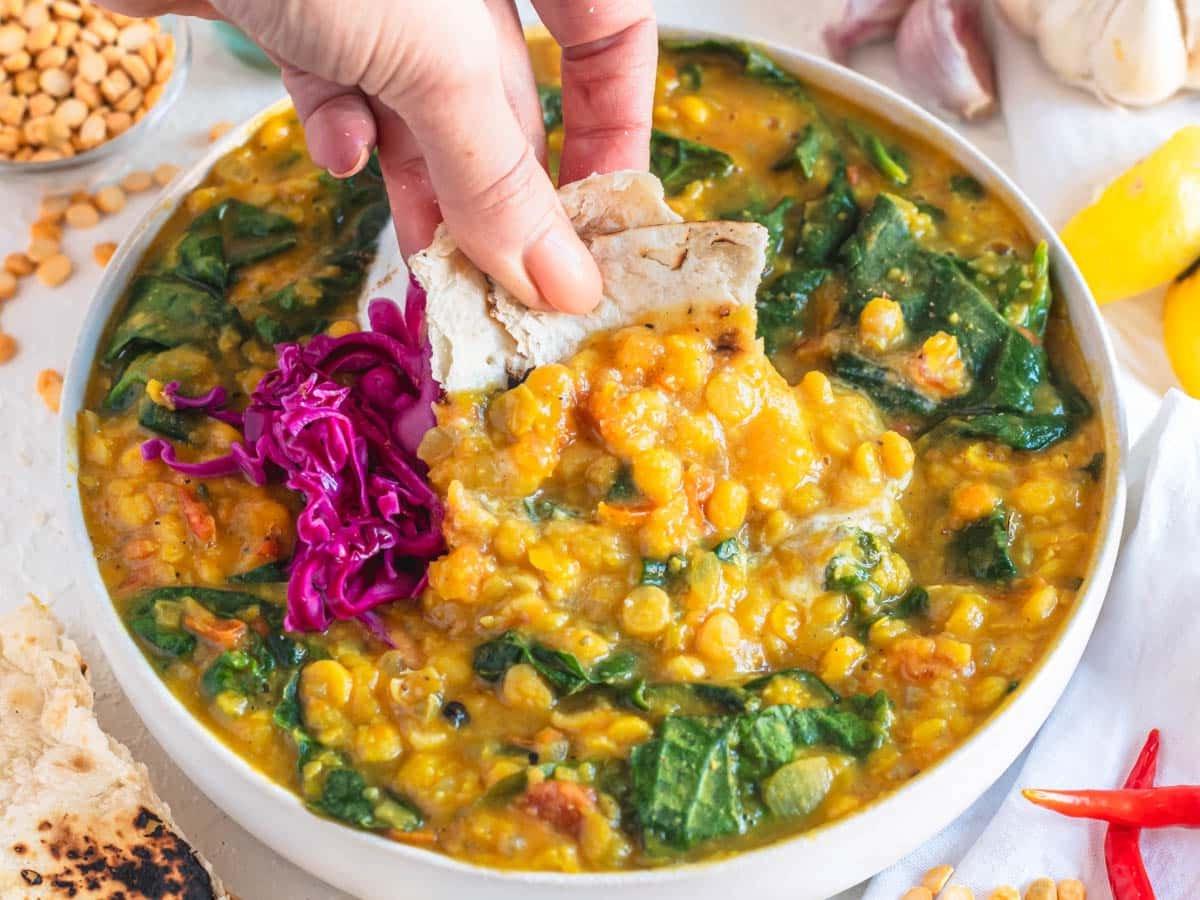 Chana Dal mit Spinat und einer Hand, die Chapati-Brot hält