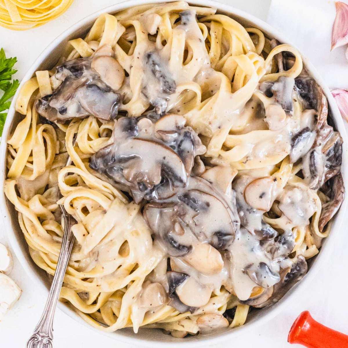 Pilz-Alfredo-Sauce mit Fettuccine und einer silbernen Gabel.