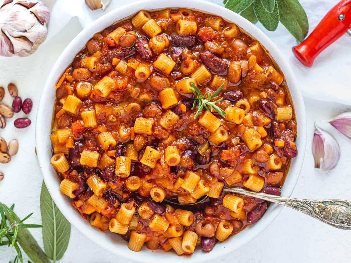 Pasta e Fagioli mit einem silbernen Löffel und Knoblauchzehen