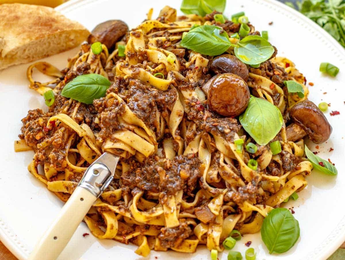 Pilz-Bolognese mit frischem Basilikum und einer Gabel