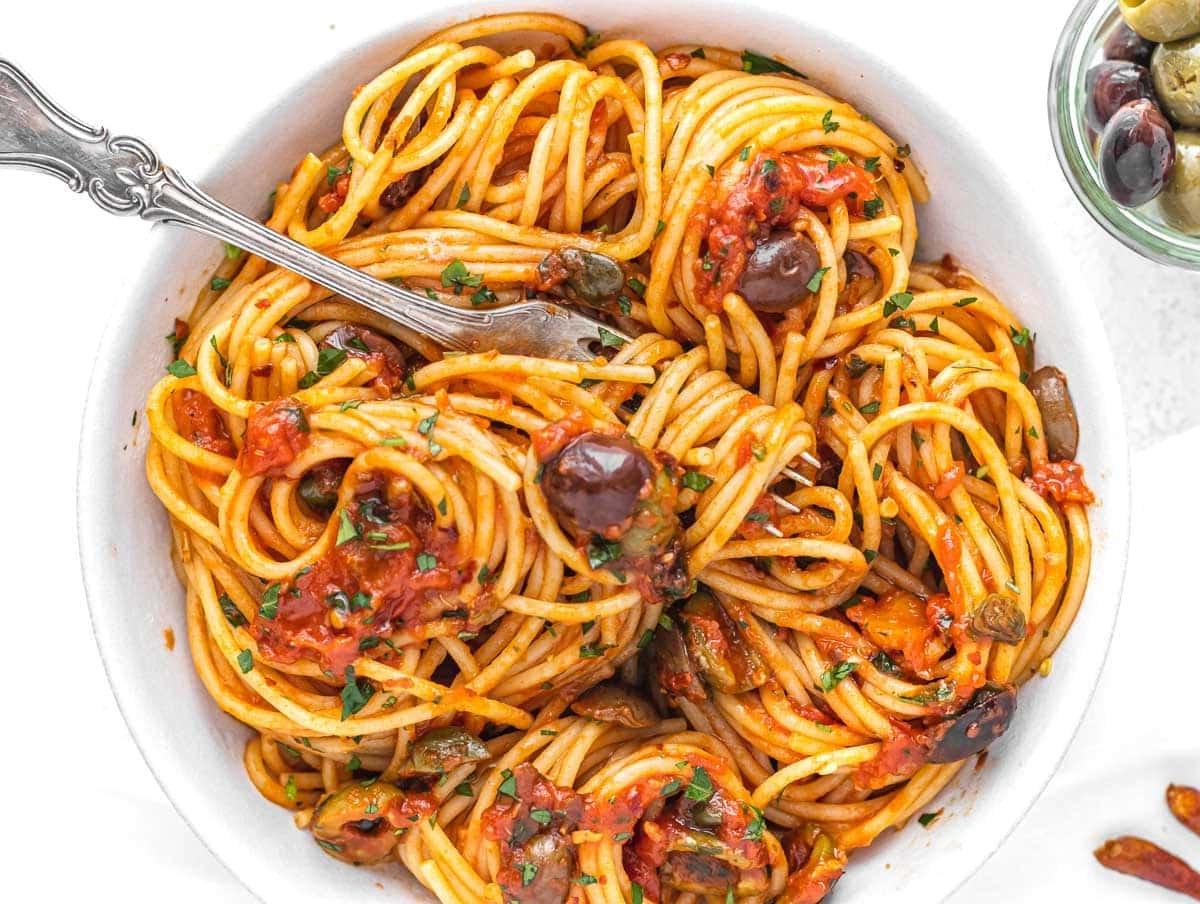 Pasta Puttanesca mit einer Gabel, ein würziger italienischer Klassiker.