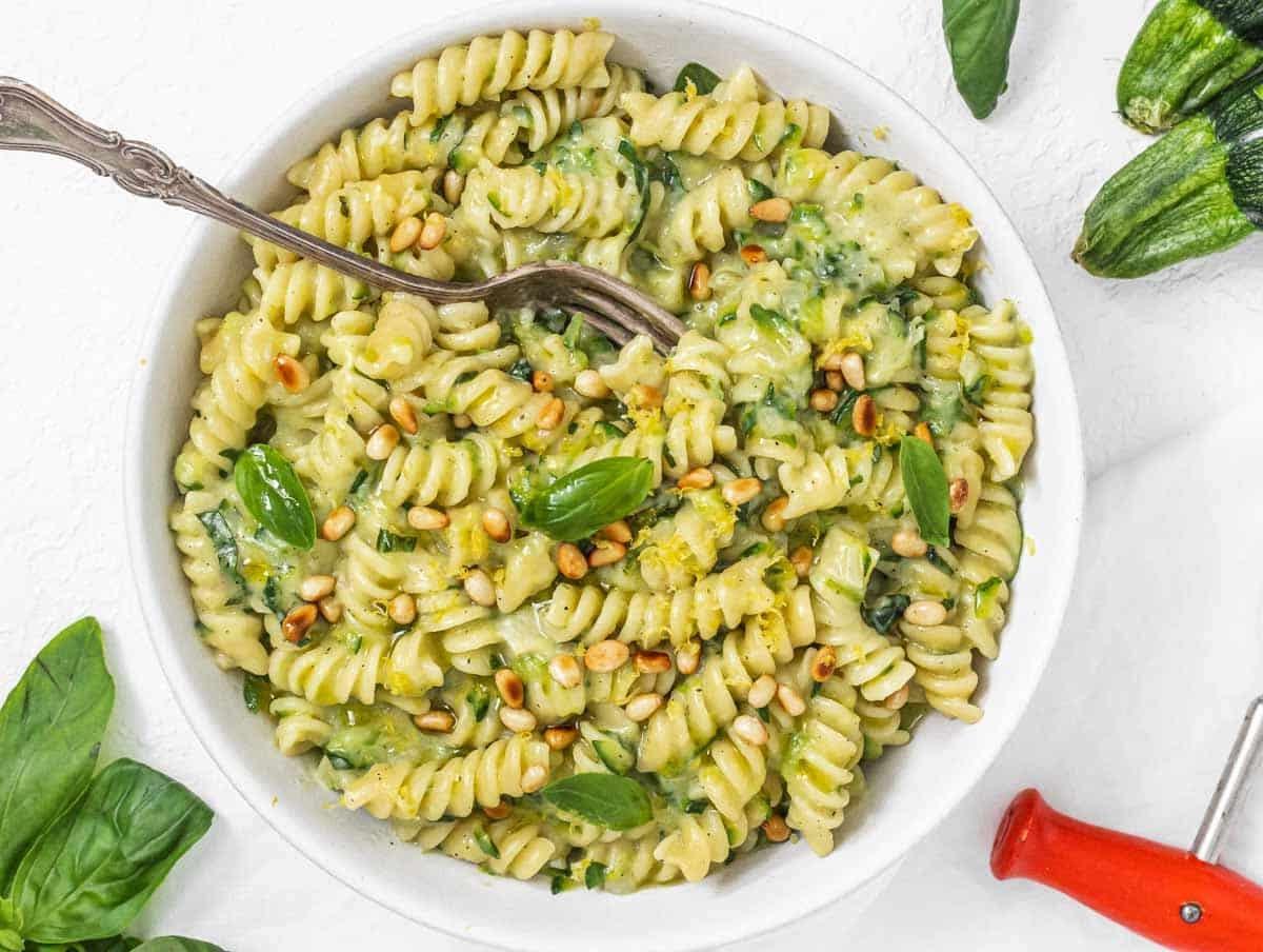 Zucchini-Pasta mit Gabel und Pinienkernen