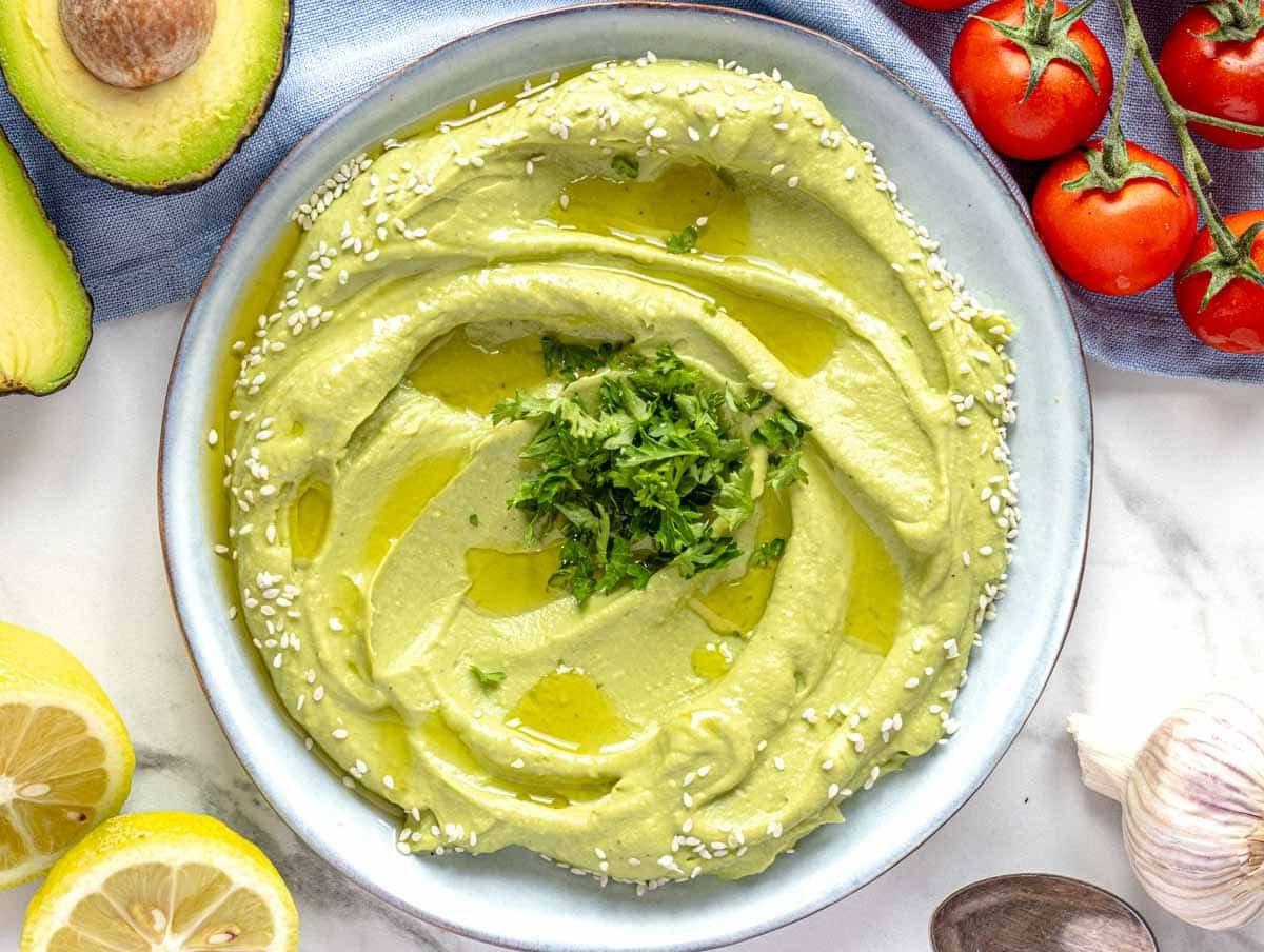 Cremiger Avocado-Aufstrich auf einem blauen Teller.