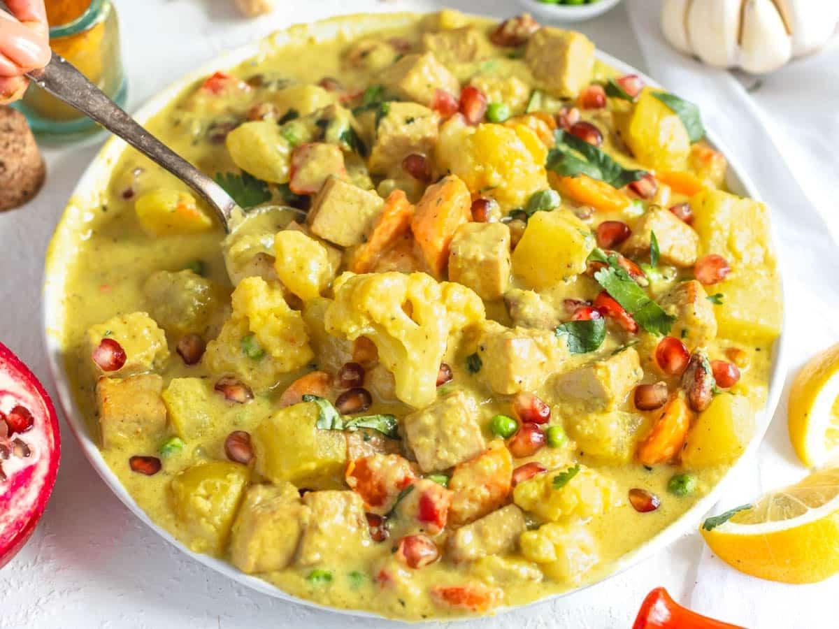 Navratan Korma auf einem weißen Teller mit einem silbernen Löffel