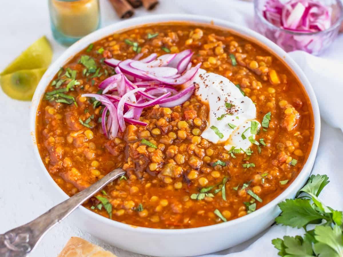 Marokkanische Linsen-Suppe mit einem silbernen Löffel und eingelegten roten Zwiebeln