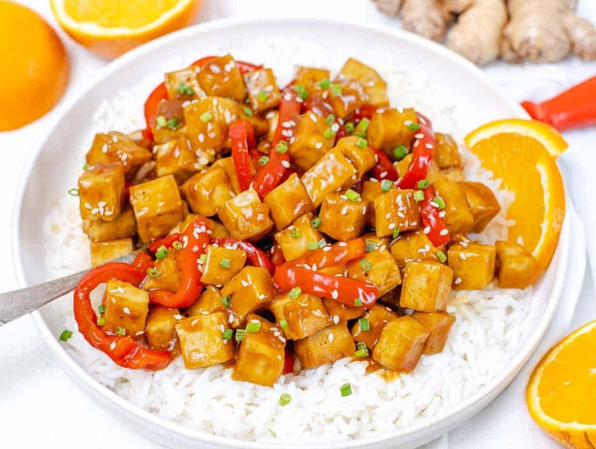 Orangen-Tofu auf einem Teller mit Reis und einem Löffel.