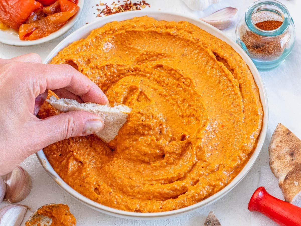 Romesco-Rezept als Dip mit Hand und Pitabrot serviert