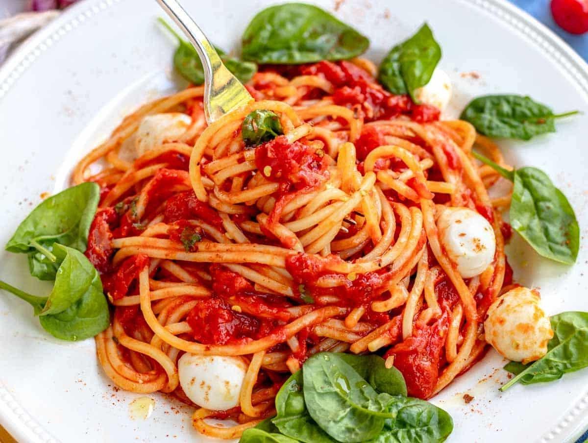 Pomodoro-Pasta mit einer Gabel und Mozzarella-Kugeln
