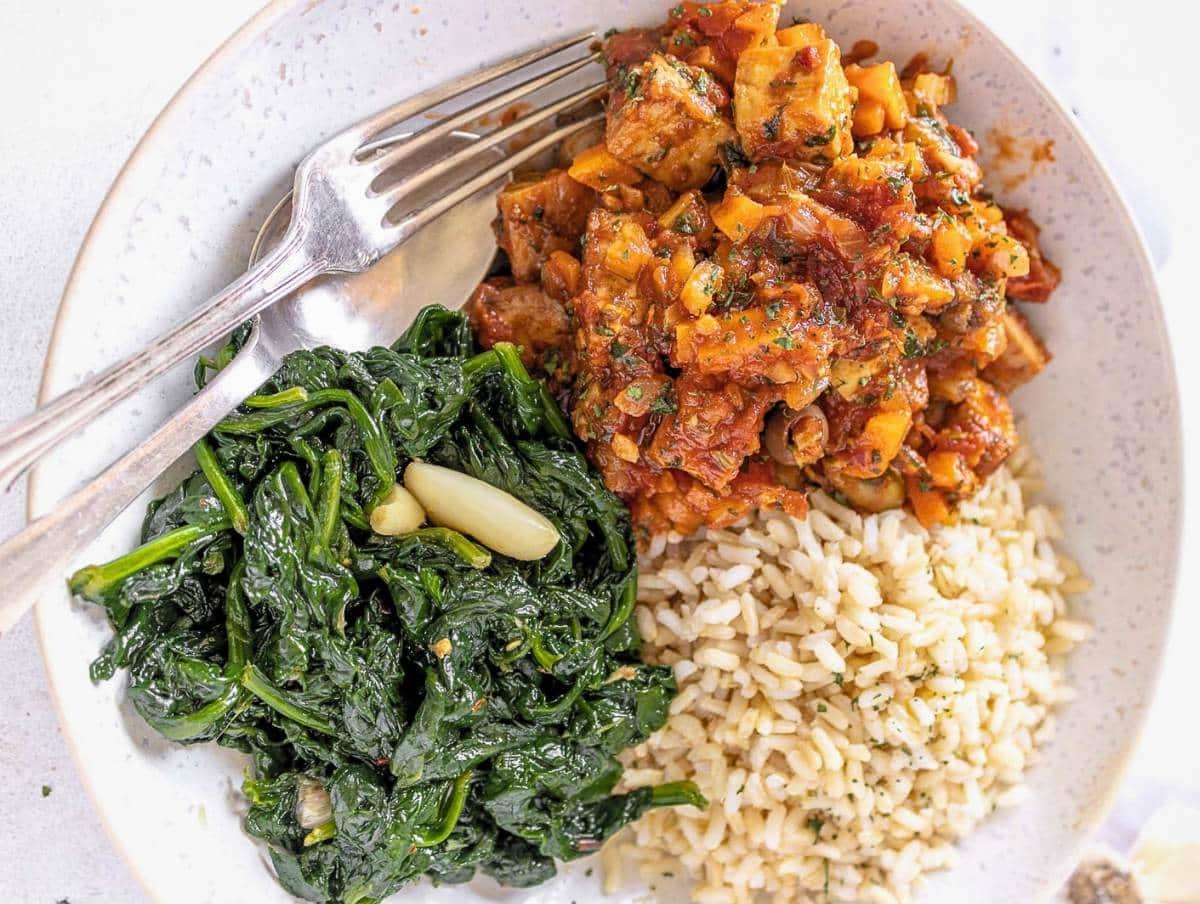 Tofu nach Jägerart 4 Vegetarian cacciatore in a white bowl with sautèed kale and rice.