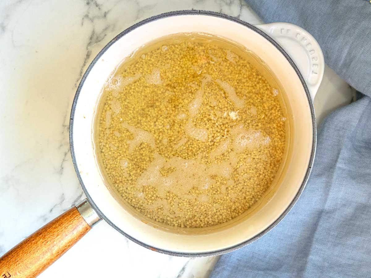 Quinoa in einem Topf mit reichlich Wasser beim Kochen.