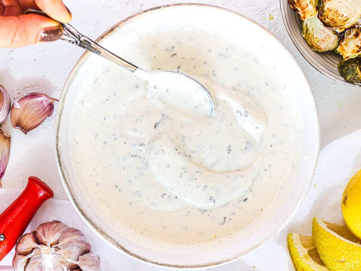 Veganes Ranch Dressing mit Hand und Silberlöffel