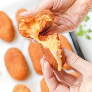 Hausgemachte italienische Suppli mit geschmolzenem Käse und weiblichen Händen.