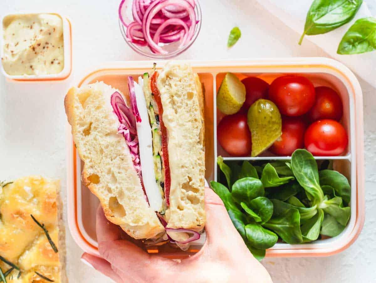 Focaccia Sandwich in einer Bento Box und eine Hand, die es hält