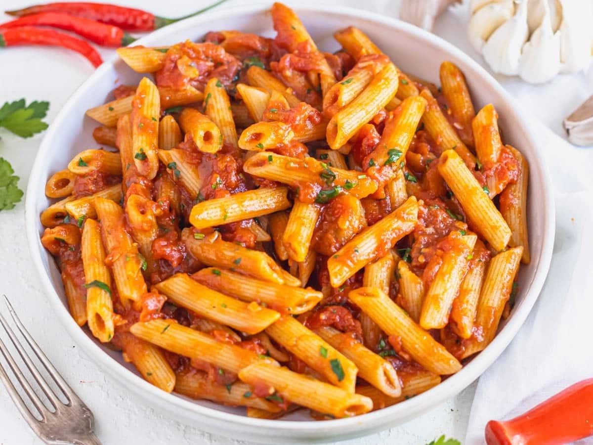 Penne Arrabbiata in einer weißen Schüssel mit frischer Petersilie.