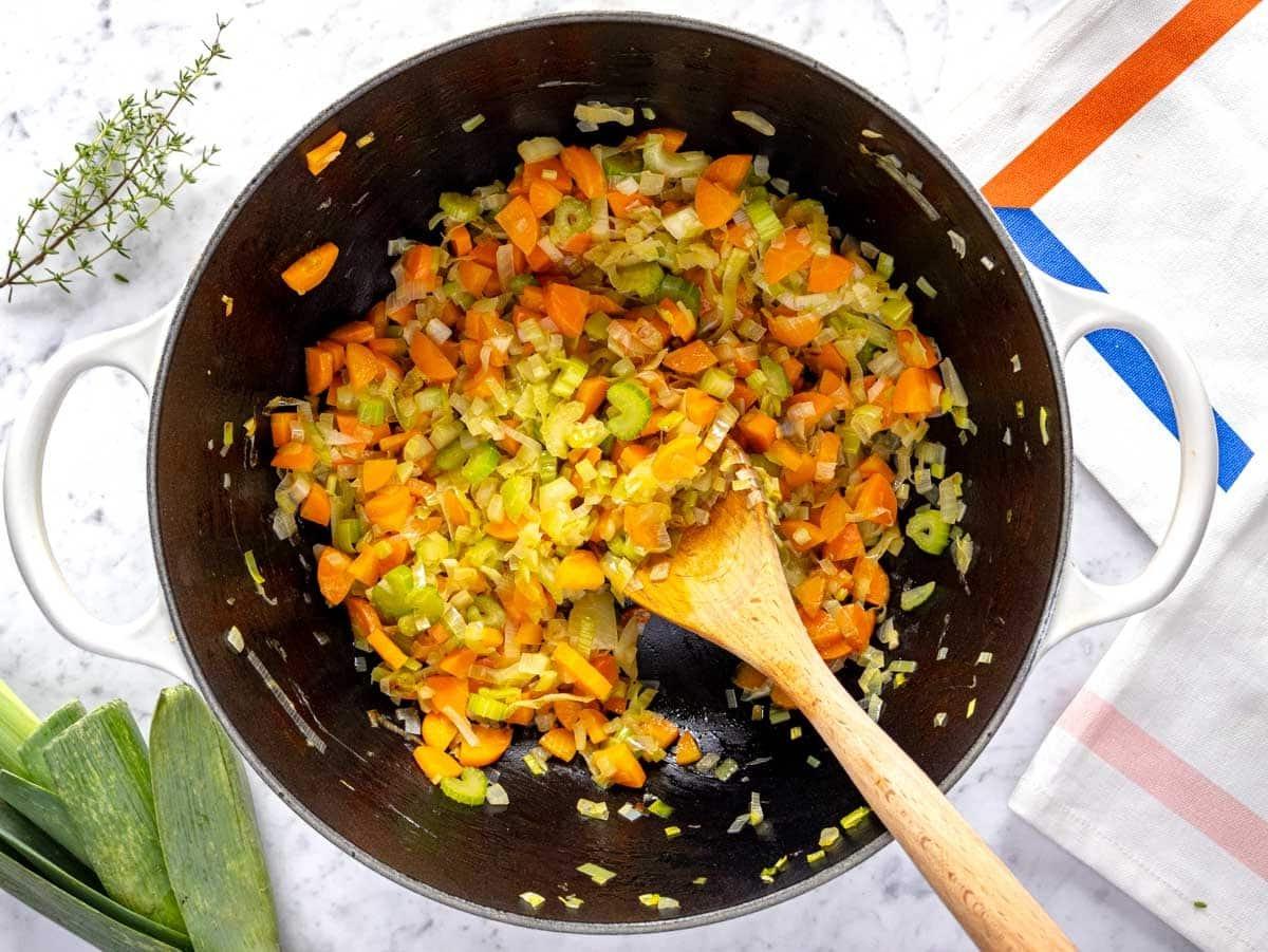 Geschmacksbasis mit Zwiebeln, Karotten, Lauch und Sellerie in einem großen Topf