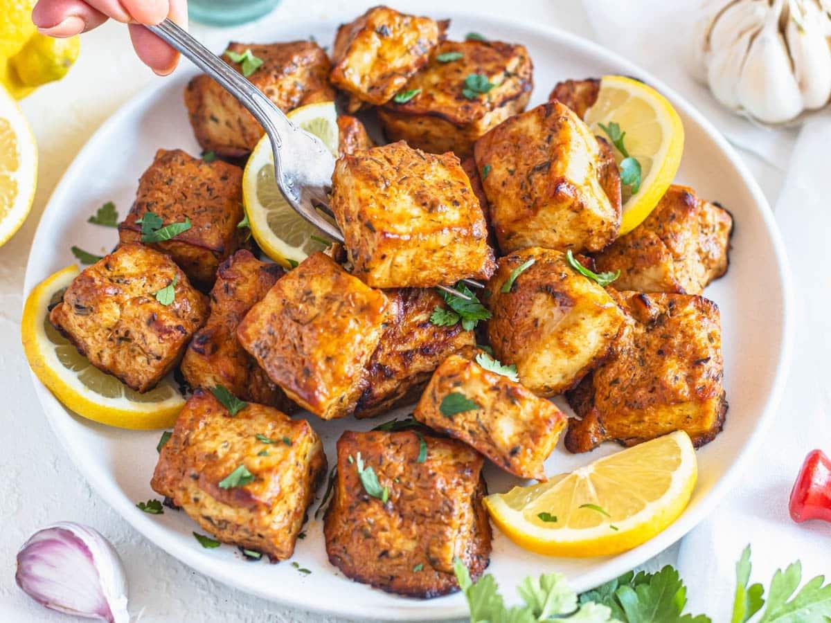 Marinierter Tofu auf einem weißen Teller mit Zitrone