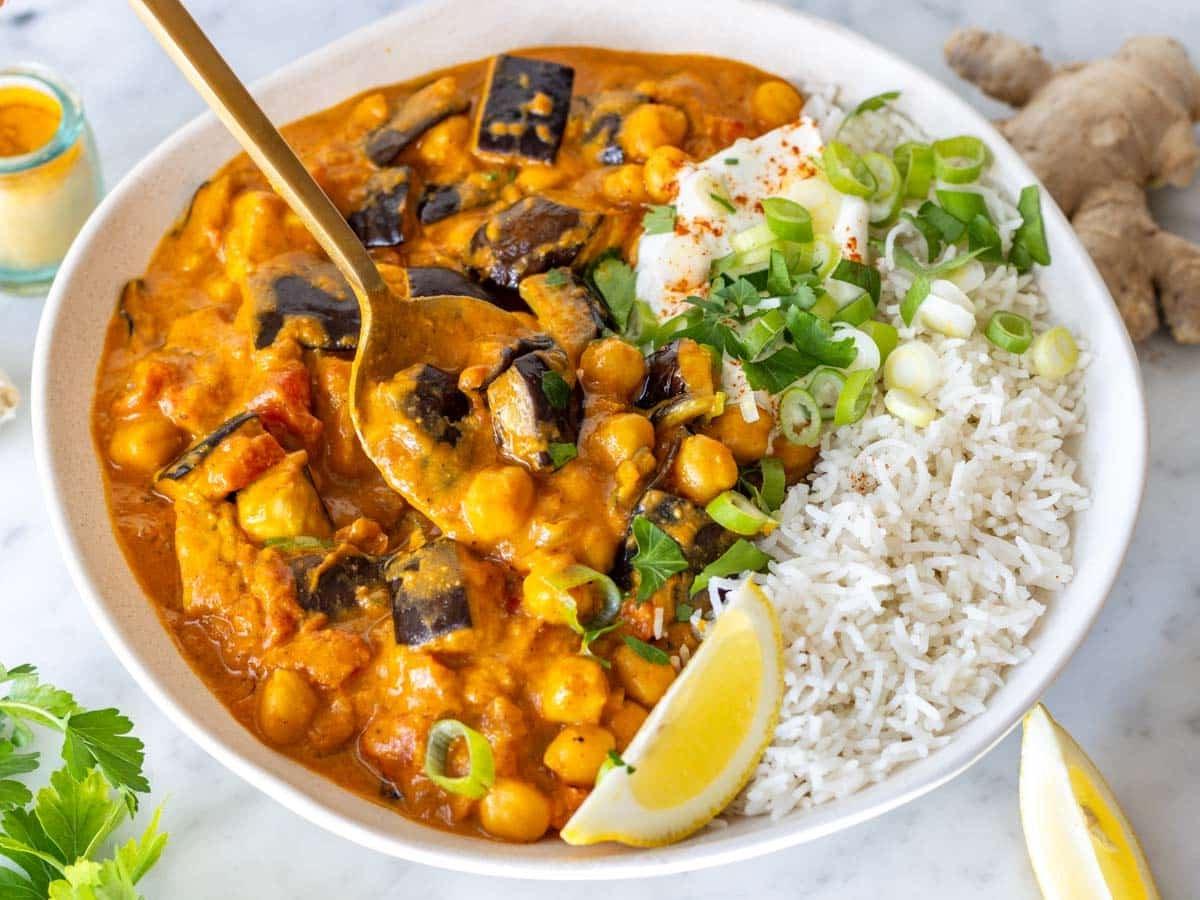 Cremiges Auberginen-Curry in einer weißen Schüssel mit Reis.