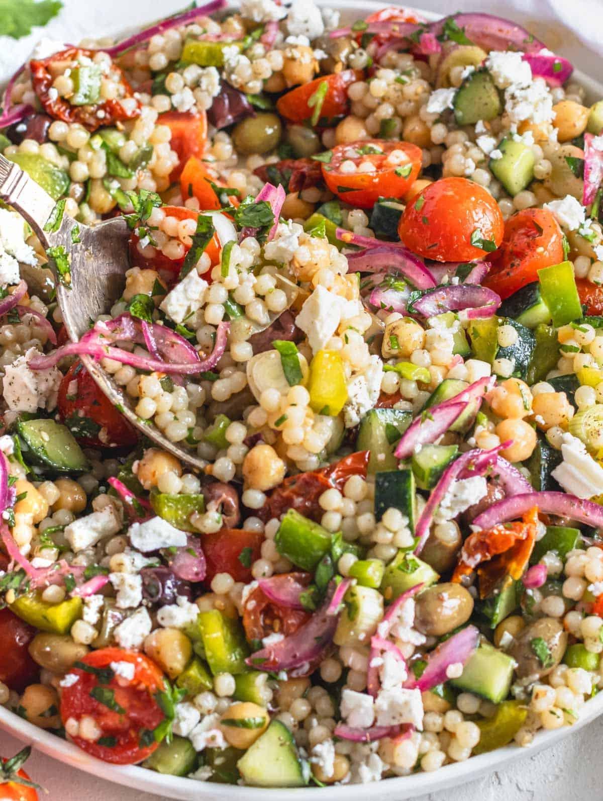 Ansprechend präsentierter Perlcouscous Salat mit zerbröseltem Feta und frischem Gemüse.