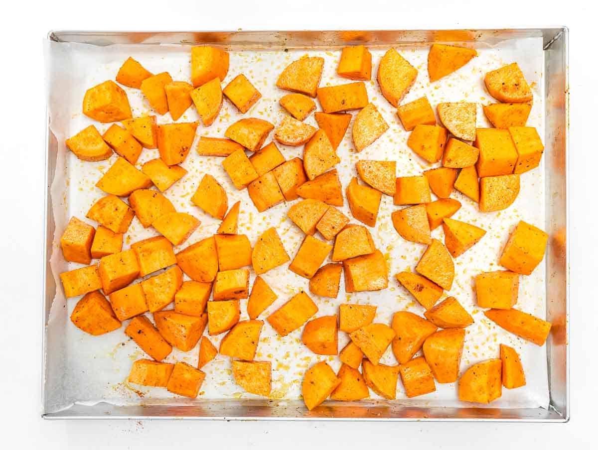 Süßkartoffelwürfel auf einem Backblech mit Olivenöl, Salz und Pfeffer