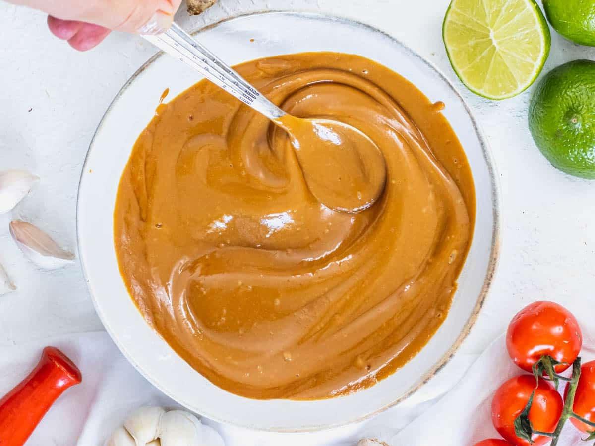 Erdnusssoßenrezept 7 Peanut sauce in a white bowl with a spoon