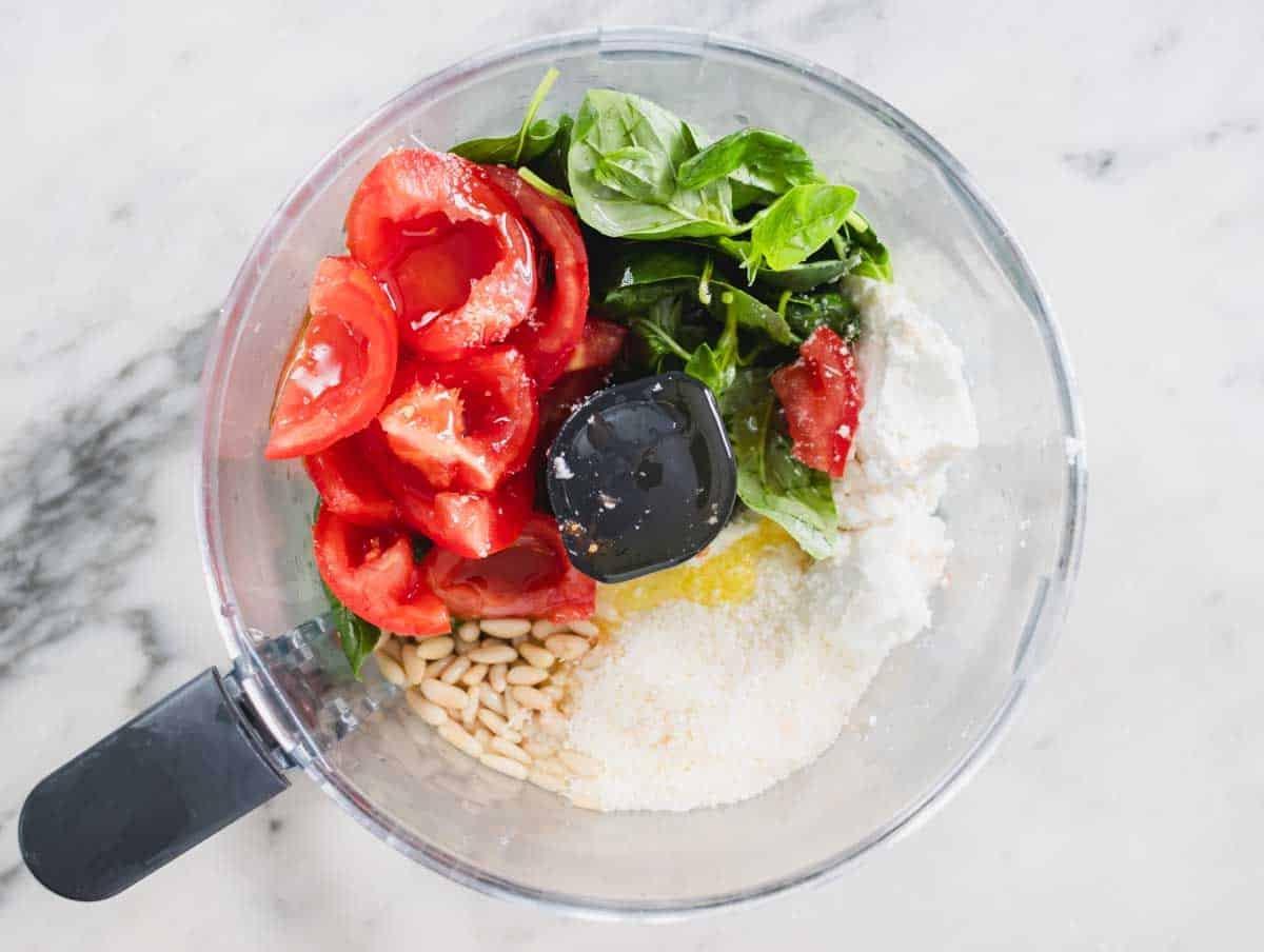 Basilikum, Käse, Pinienkerne und Tomaten in einem Food Processor