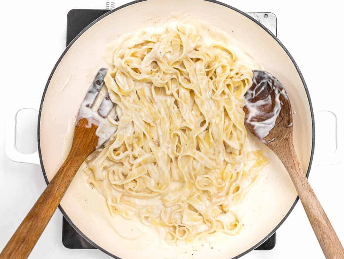 Cremige Alfredo-Soße ohne Sahne in einer Pfanne, perfekt vermischt mit Pasta – ein einfaches und gesundes Gericht.