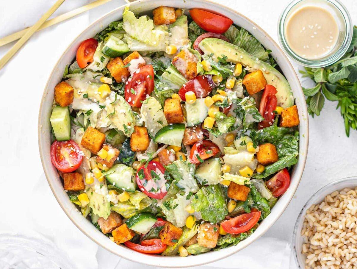 Fertiger Tofusalat mit Tahini-Dressing und Avocado-Stückchen, angerichtet zum Verzehr.