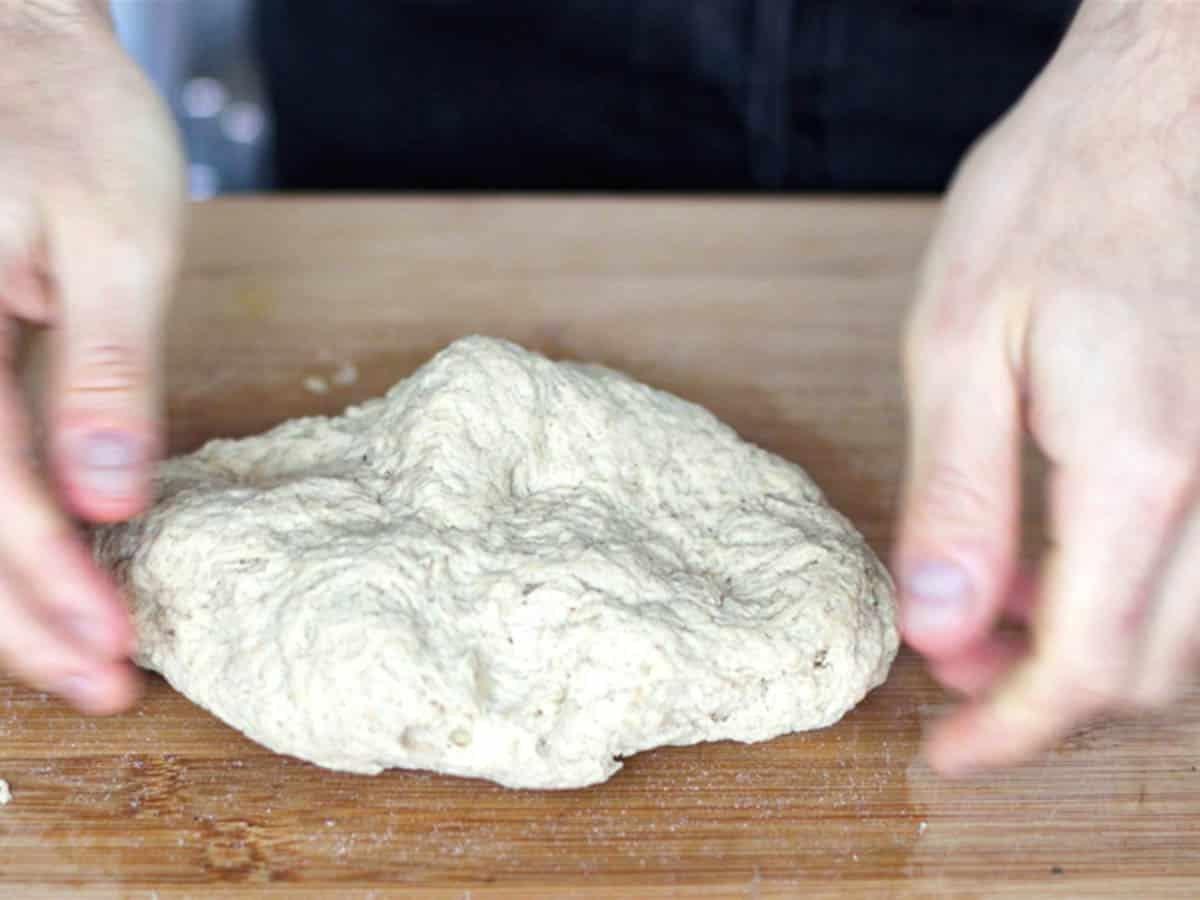 Hände kneten Seitan auf einer Küchenplatte