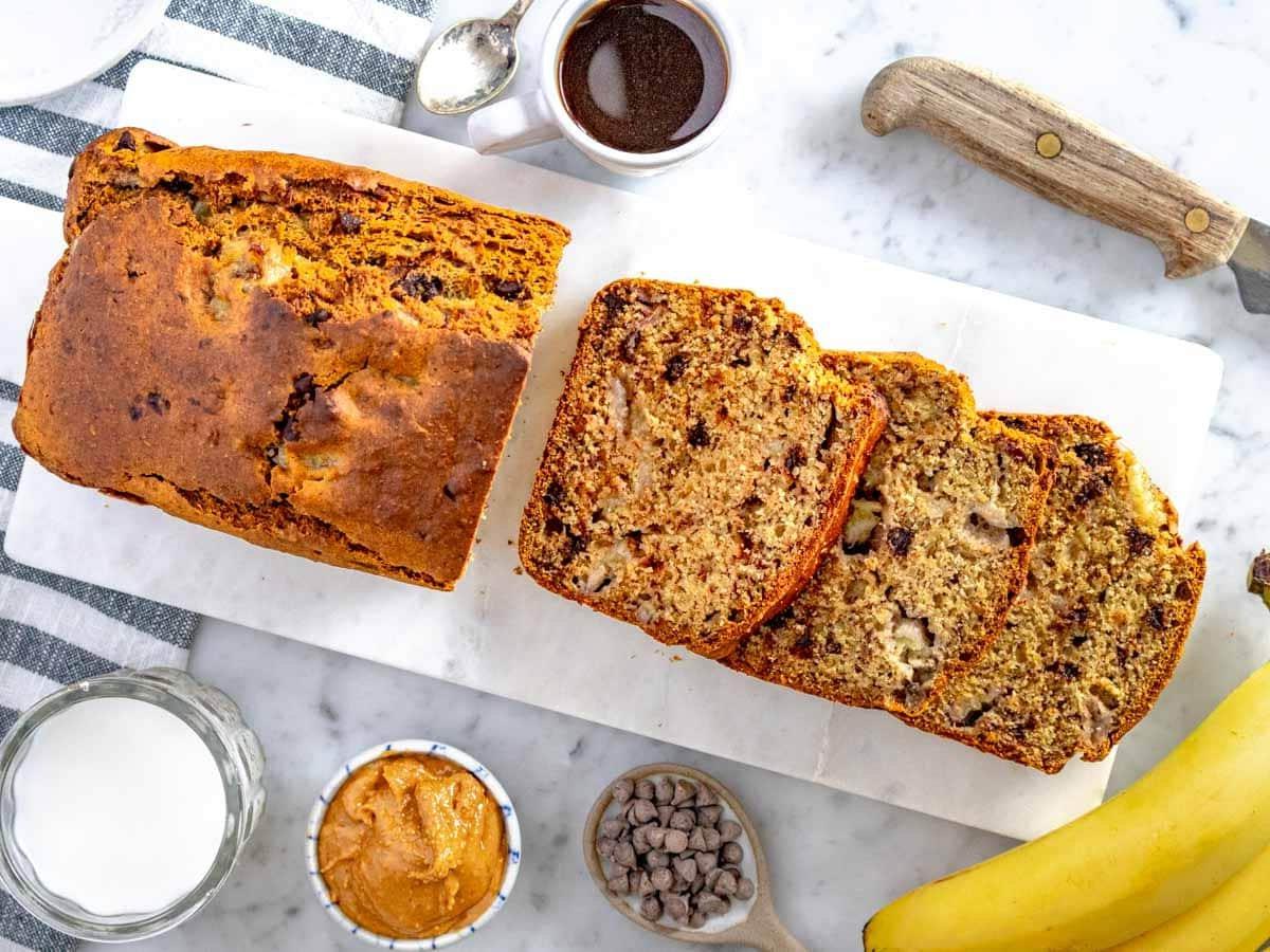 Scheiben und Laib gesundes Bananenbrot serviert mit Kaffee und Erdnussbutter