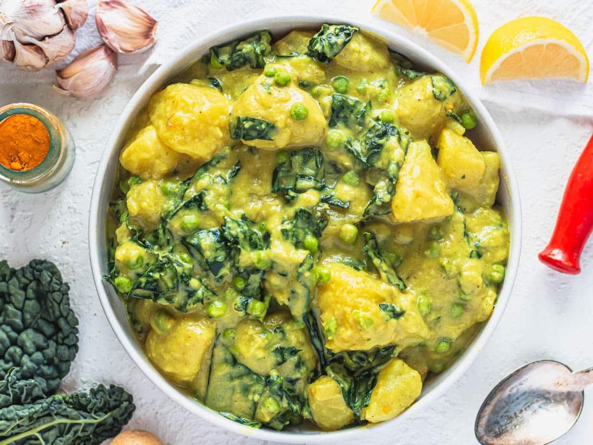 20 einfache Curry-Rezepte 9 Kartoffel-Curry in einer weißen Schale mit Zitrone und Knoblauch an der Seite