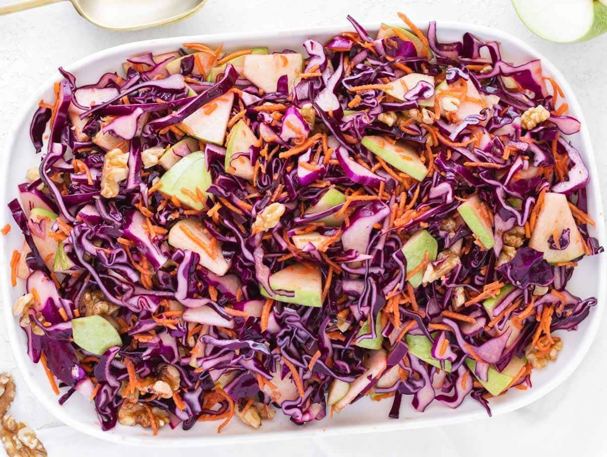 Essig-Krautsalat auf einer weißen Servierplatte angerichtet.