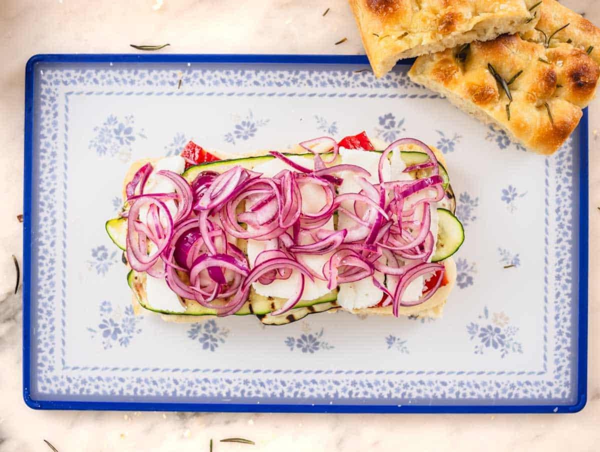 Focaccia Sandwich mit Gemüse und eingelegten roten Zwiebeln auf einem Schneidebrett