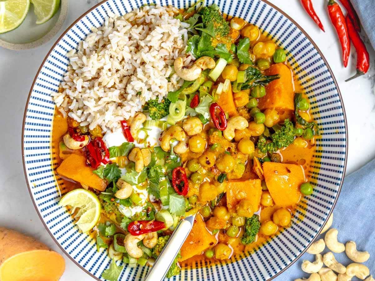 Gemüse-Curry serviert mit Reis, Limette und Cashewkernen