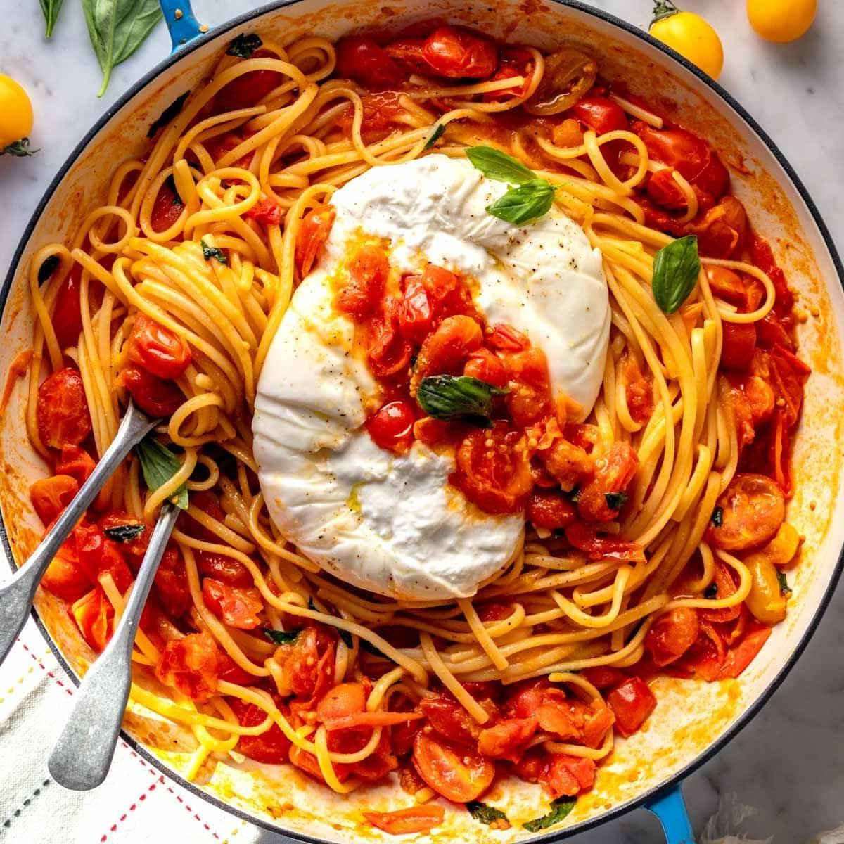 Kirschtomaten-Pasta mit Burrata in einer blauen Pfanne, frisch zubereitet.