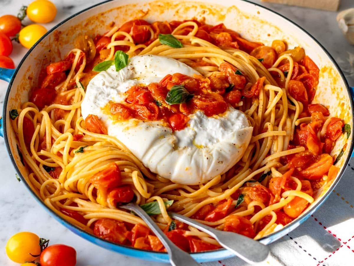 Kirschtomaten-Pasta in einer blauen Pfanne mit Burrata-Käse serviert.