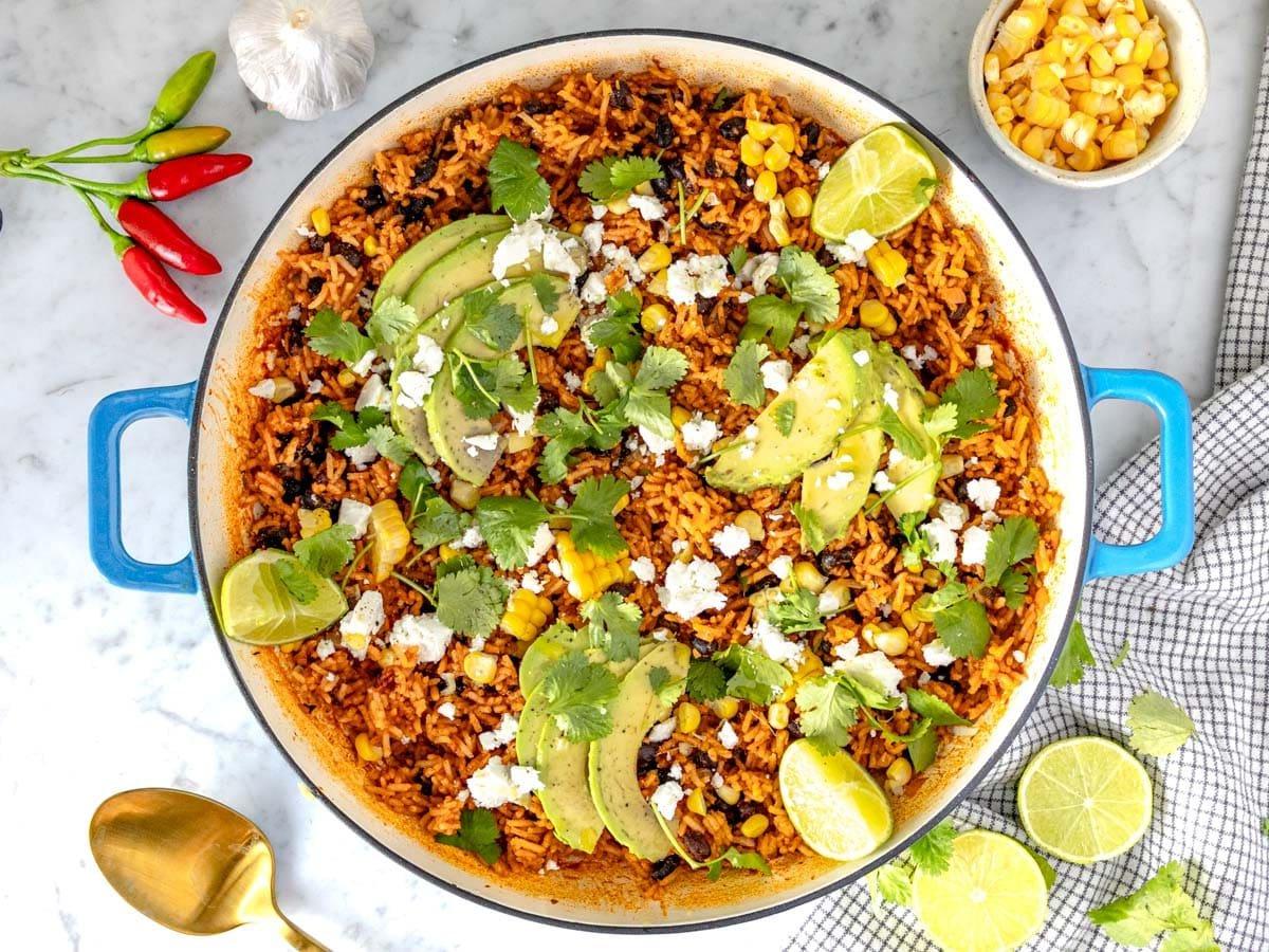 Mexikanischer Reis mit Avocado, Queso Fresco, Limettensaft, Mais und Koriander garniert