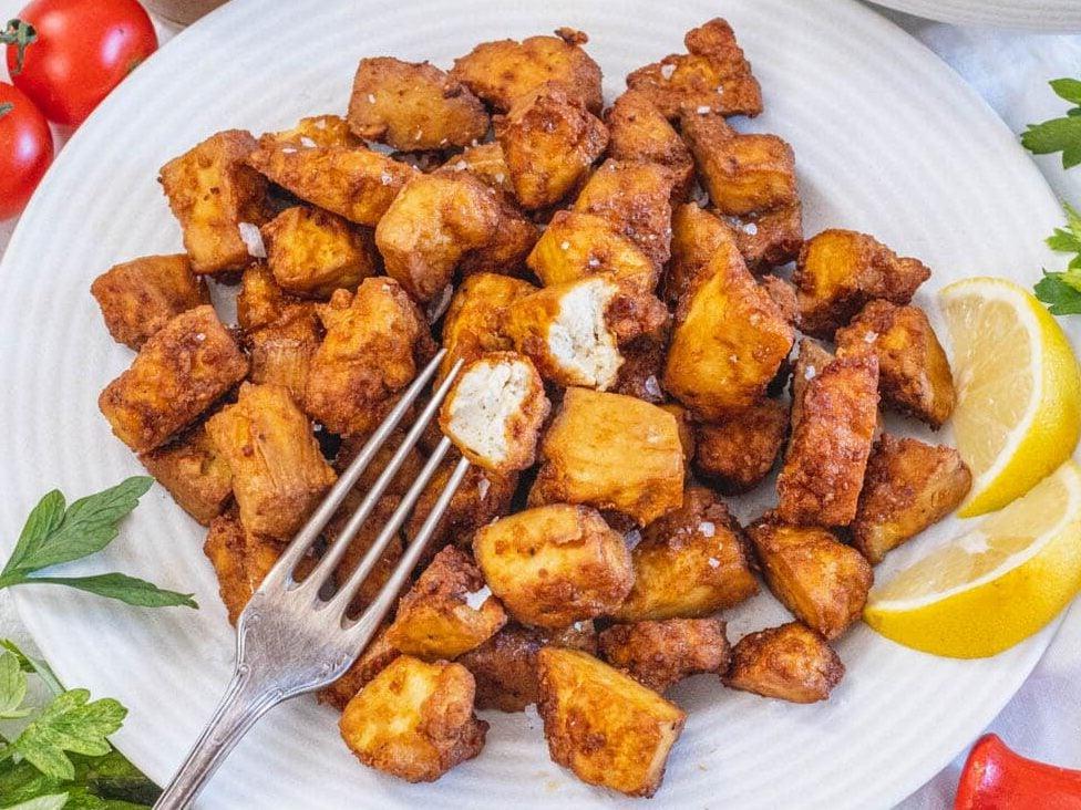Tofu aus der Heißluftfritteuse auf einem Teller mit Zitronenspalten.